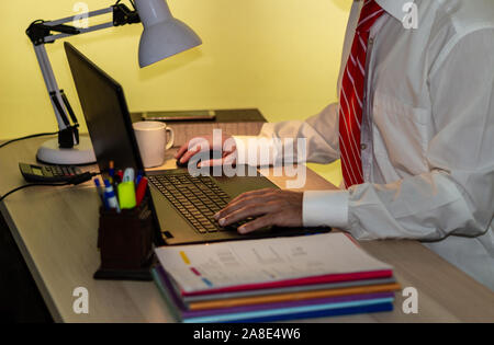 Man in suit works with laptop computer in office. Business man in white shirt with red tie works Stock Photo