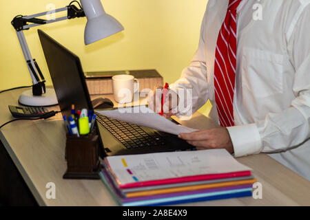 Man in suit works in office, executive man signing document. Businessman in white shirt with red tie works Stock Photo