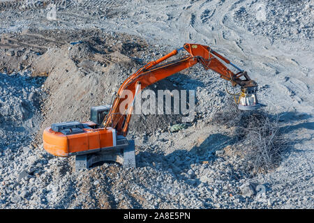 Excavator with a magnet on the boom for loading metal waste cargo Stock Photo