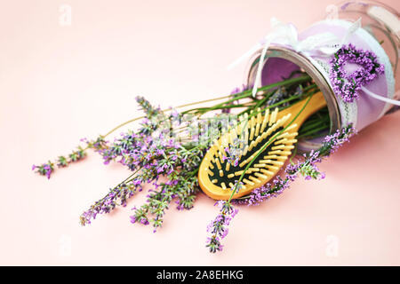 Wooden scalp and massage brush and hair comb with lavender flowers on pastel pink background. Toned, close-up, vintage style. Stock Photo