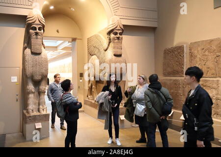 Visitors in front of Assyrian winged bulls from Khorsabad at the British Museum, London, UK