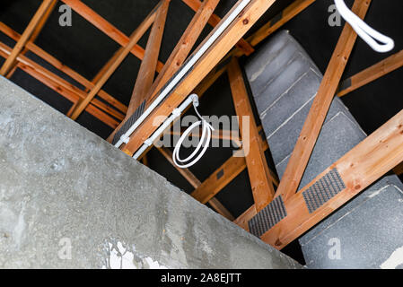Lighting cables in plastic wiring pipes in a newly built house mounted on roof trusses. Stock Photo