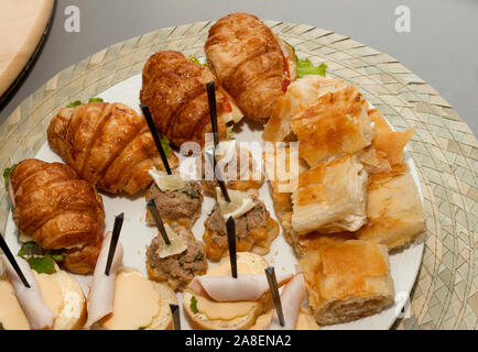 A plate of different kinds of appetizers, Party food closeup on a plate. Bread rolls with grapes, meat and prawn. Stock Photo