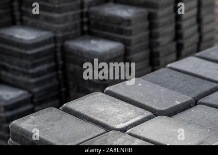 Stack of paving stone on construction site. Bricks for paving stones stacked in stacks, background texture structure. Gray pavement bricks for Stock Photo