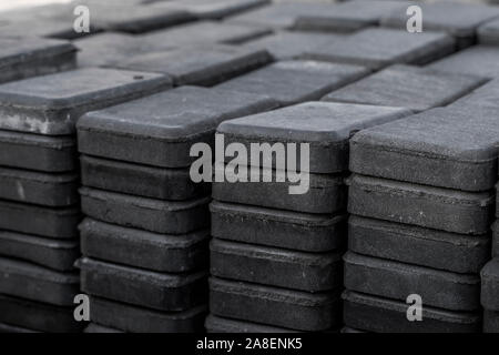 Stack of paving stone on construction site. Bricks for paving stones stacked in stacks, background texture structure. Gray pavement bricks for Stock Photo