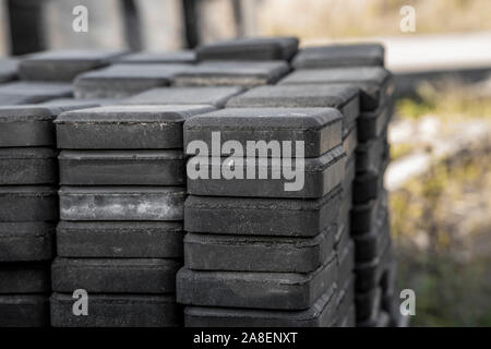 Stack of paving stone on construction site. Bricks for paving stones stacked in stacks, background texture structure. Gray pavement bricks for Stock Photo