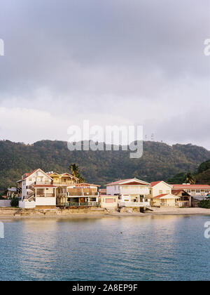 Beach houses, bars, and restaurants lining a calm harbor at sunset in the Grenada islands Stock Photo