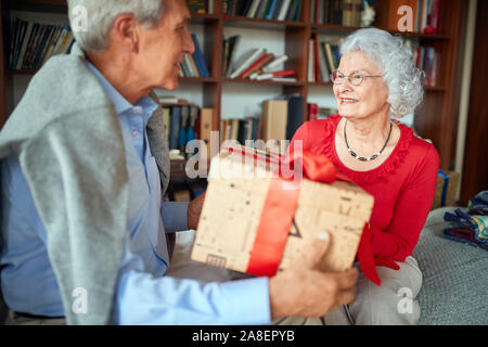 lovely Senior Couple Exchanging Christmas Gifts at Home at Christmas morning. Stock Photo