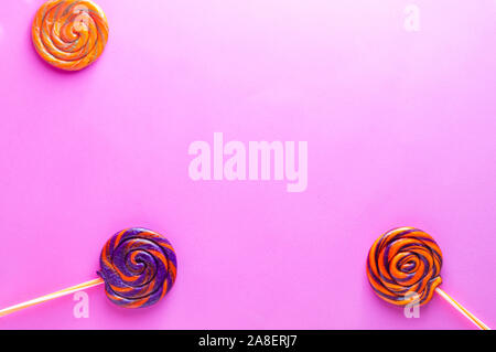 Colorful candy lollipops isolated on pink background. Orange, purple and green sweet lollies. Stock Photo