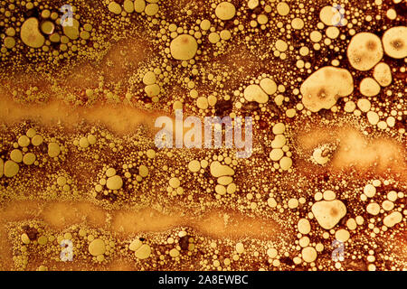 abstract background with rusty colored oil bubbles on water with soap foam Stock Photo