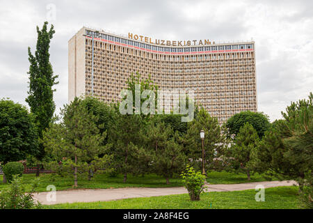 The Russian built Hotel Uzbekistan behind trees in full leaf at Independance Square, Tashkent Stock Photo