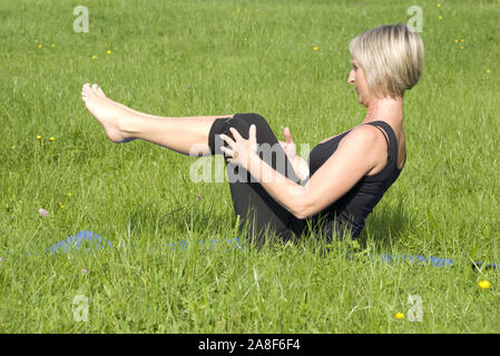 Frau macht Pilates auf einer Wiese, MR: Yes Stock Photo
