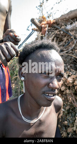 Young Dassenech man given haircut Omorate Ethiopia Stock Photo