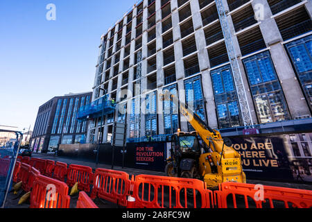 A JCB driver works on the new Hilton Hotel building, structure in Stoke on Trent, Hanley, loading and unloading materials for his work colleagues Stock Photo