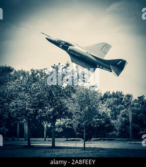 A low flying vintage US Navy Blue Angels airplane banking over treetops in the USA