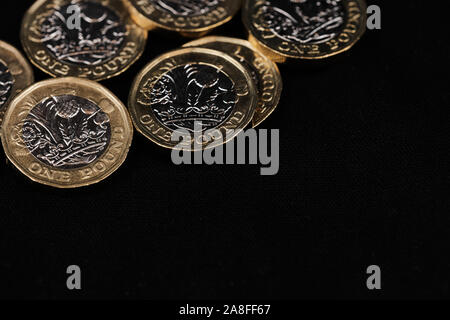 one pound coins in the left corner on the top against black background with copy space Stock Photo