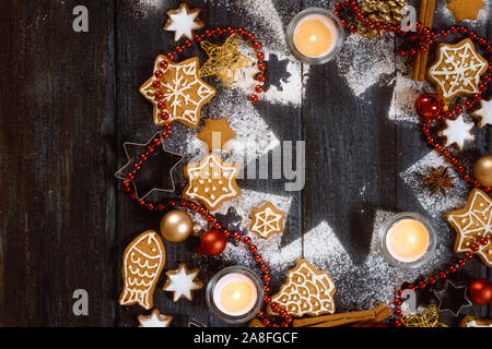 Gingerbread cookies, spices and burning candles on a star shape from icing sugar on a dark rustic wooden background, Christmas composition with copy s Stock Photo