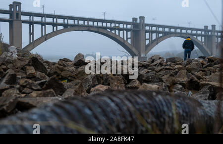 River pollution of industry. dirty industrial pipe polluting river. fisherman fishes in a dirty river. bridge over river Stock Photo