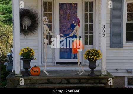 Two skeletons are dancing on the front porch of a house dressed up for Halloween, fall, Maine USA Stock Photo