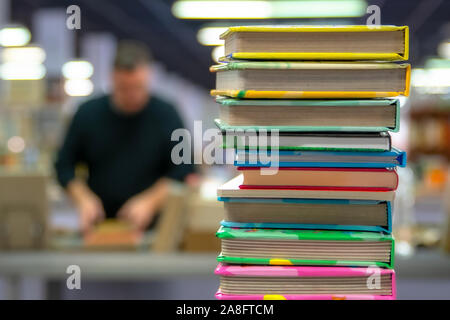 A stack of books on the blurred background of the bookstore. The concept of education and knowledge from books. Close up. With space for text or logo. Stock Photo