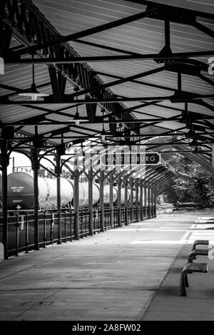 Overhead canopy for Passengers waiting area for boarding at the Hattiesburg, MS, train depot, with nameplate sign and oil tankers nearby, Hattiesburg, Stock Photo