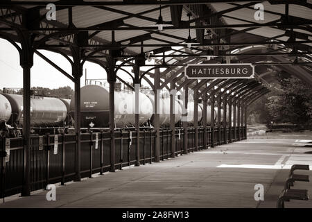 in Overhead canopy for Passengers waiting area for boarding at the Hattiesburg, MS, train depot, with nameplate sign and oil tankers nearby, Hattiesbu Stock Photo