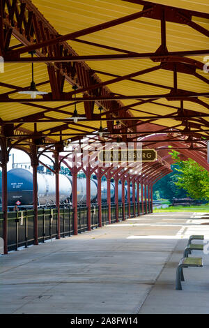 Covered Passenger waiting area for boarding at the Hattiesburg, MS, train depot, with nameplate sign and oil tankers nearby, Hattiesburg, MS, USA Stock Photo