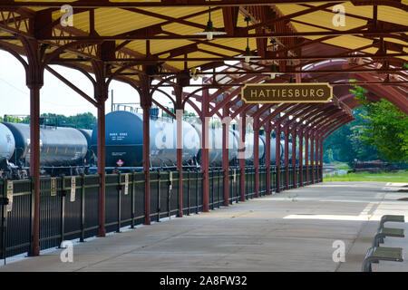 Overhead canopy for Passengers waiting area for boarding at the Hattiesburg, MS, train depot, with nameplate sign and oil tankers nearby, Hattiesburg, Stock Photo