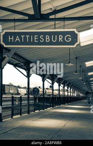 Overhead canopy for Passengers waiting area for boarding at the Hattiesburg, MS, train depot, with nameplate sign and oil tankers nearby, Hattiesburg, Stock Photo