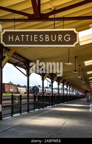 Overhead canopy for Passengers waiting area for boarding at the Hattiesburg, MS, train depot, with nameplate sign and oil tankers nearby, Hattiesburg, Stock Photo