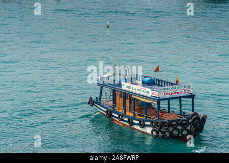 Nha Trang, Vietnam - March 11, 2019: Closeup of traditional colored Green Star Dive Center boat sitting on azure water. Stock Photo