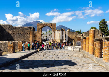 View of Via del Foro in the ancient city of Pompeii with the Arch of Caligula and Mount Vesuvius in the background. Pompeii, Italy, October 2019