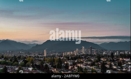 View of East Vancouver and downtown of Brentwood, Burnaby skylines with mount Seymour backdrop lit by last sun rays before sunset Stock Photo