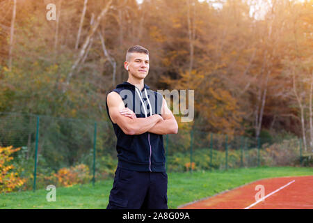 Portrait of a young man jogger in the morning outdoors standing on running race track Stock Photo