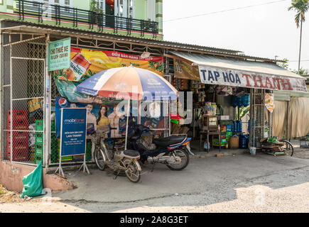 Nha Trang, Vietnam - March 11, 2019: Grocery store in rural Phuoc Trach neighborhood adds colors to its front by displaying advertisements. Motorcycle Stock Photo