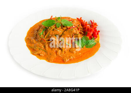 Dried red curry pork with coconut milk (Panang) Thaifood curry style topped with bergamot leaf slice and chili side view isolated on white background Stock Photo