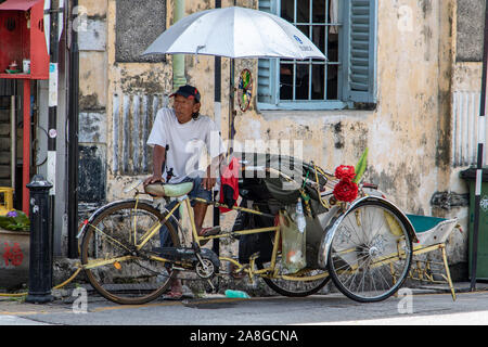 PENANG, MALAYSIA, NOV 12 2017, a traditional tricycle in the street of Penang. A driver decorated rickshaw waits for a passenger. Stock Photo