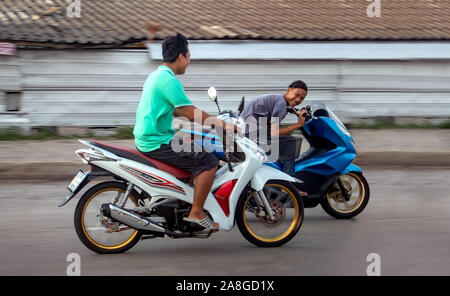 SAMUT PRAKAN, THAILAND, APR 27 2019, Guys on motorbikes racing on the city street. Two Asian young men ride fast on motorbikes on the road. Stock Photo