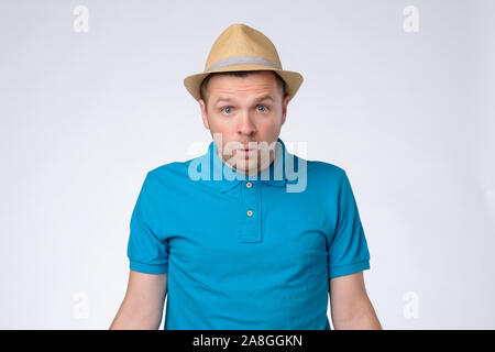 Confused handsome guy in summer hat and blue t-shirt. Studio shot Stock Photo