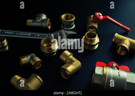 Plumbing equipment on a black background. Valves and wrench Stock Photo