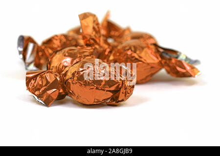 Chocolate sweets wrapped in aluminum foil against white background Stock Photo