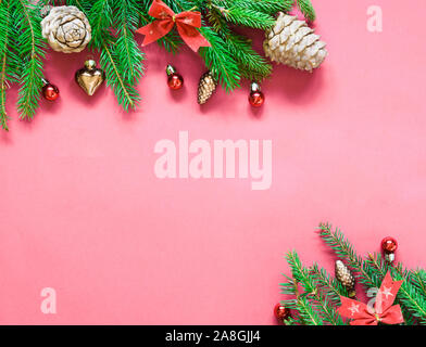 top view, green branches of spruce together with New Year's toys and bows on a pink background Stock Photo