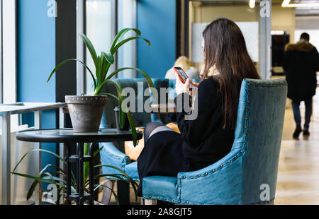 weekend concept in modern society, girls in a cafe sitting at a table drinking coffee and looking at the phone Stock Photo