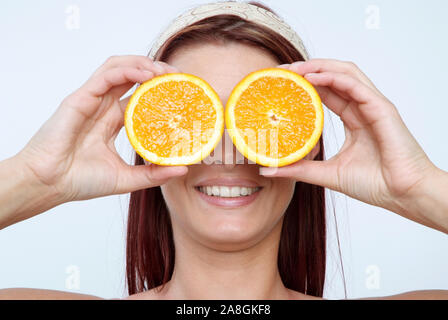 Junge Frau hält sich Orangen vors Gesicht, MR: Yes Stock Photo