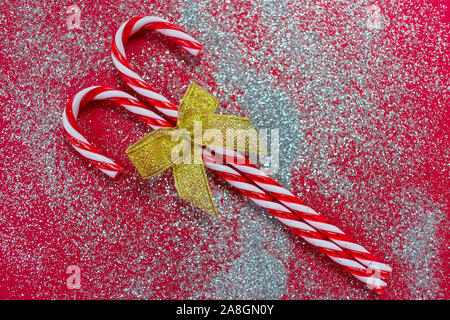 Two christmas candies with a golden bow on a shiny red background. Stock Photo