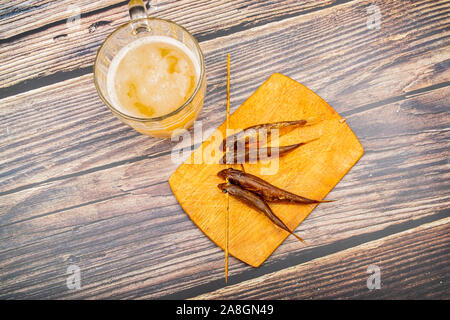 Dried mullet on a wooden Board with a mug of beer on the table. Fish and seafood cuisine. Tasty snack Stock Photo