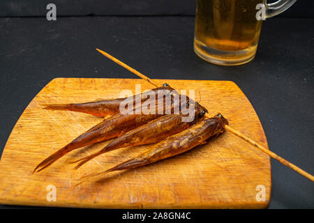 Dried mullet on a wooden Board with a mug of beer on the table. Fish and seafood cuisine. Tasty snack Stock Photo