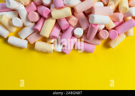Multi-colored little marshmallows on a bright yellow background. Copy space. Stock Photo