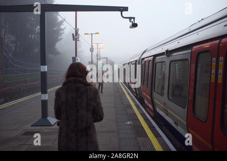 north west London, Harrow on the hill, commuters walking on the tube station platform, catching the tube to work in the tick fog morning. Stock Photo