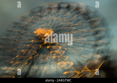 Blurred ferris wheel in motion at the amusement park, night illumination. Long exposure. Stock Photo